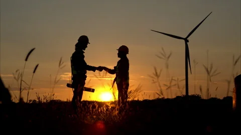 Silhouette of engineer and worker shaking hands on wind turbine background Stock Footage 259384569
