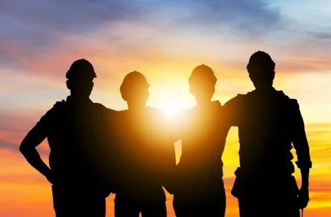 Silhouette of engineer and worker team standing with hands on shoulders 写真素材
