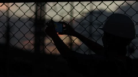 Silhouette engineer standing orders for construction crews and using phone. Stock Footage 165434019