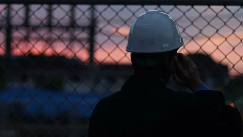 Silhouette engineer standing orders for construction crews and using phone. Stock Footage 165436731
