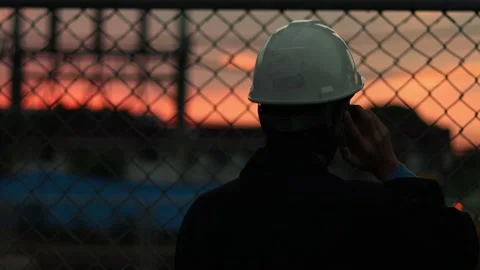 Silhouette engineer standing orders for construction crews and using phone. Stock Footage 165436988