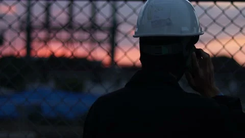 Silhouette engineer standing orders for construction crews and using phone. Stock Footage 165437179
