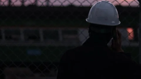 Silhouette engineer standing orders for construction crews and using phone. Stock Footage 165437230