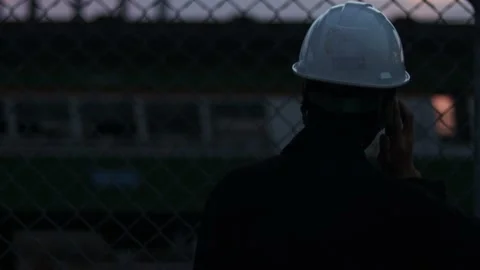 Silhouette engineer standing orders for construction crews and using phone. Stock Footage 165437234