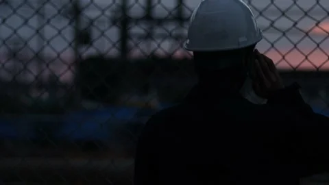 Silhouette engineer standing orders for construction crews and using phone. Stock Footage 165437699