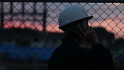 Silhouette engineer standing orders for construction crews and using phone. Stock Footage 165437730