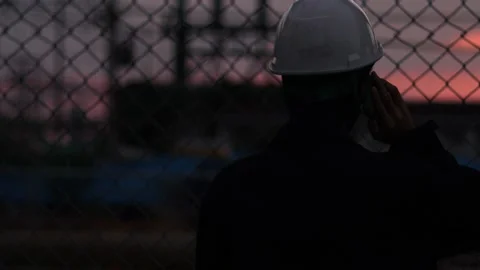 Silhouette engineer standing orders for construction crews and using phone. Stock Footage 165437745