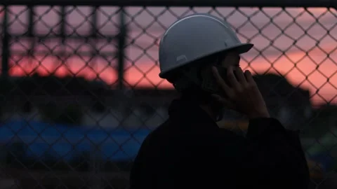 Silhouette engineer standing orders for construction crews and using phone. Stock Footage 165437747