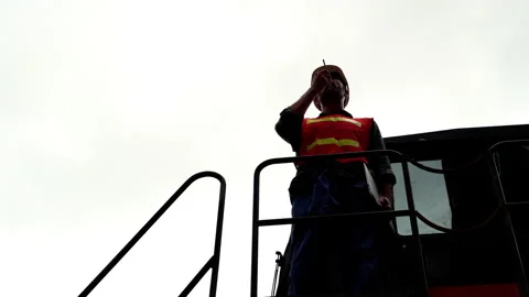 Silhouette, an engineer is using a radio to communicate on a forklift Stock Footage 132271107