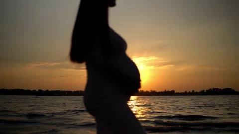 The silhouette of an expectant mother, lovingly touching her baby bump, set Stock Footage 249415692