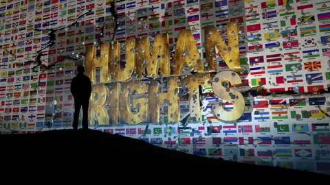Silhouette Facing Giant Human Rights Message Against a World Flags Background Stock Footage 344908909