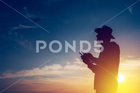 Silhouette of farmer using drone remote control Stock Photos