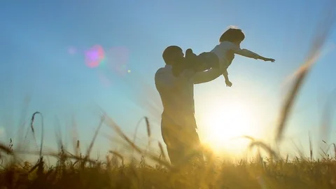 Silhouette of father and son playing, enjoying sunset in wheat field in nature Stock Footage