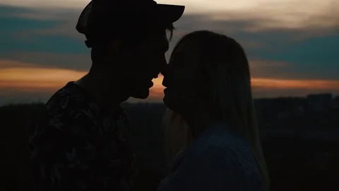 Silhouette figures in love couple at sunset. Two figures kissing at sunset Stock Footage