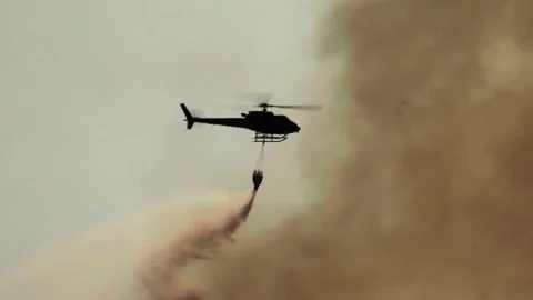 Silhouette Fire fighting helicopter dropping water on forest fire Stock Footage 147318767