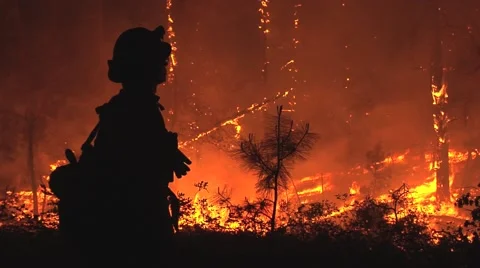 Silhouette of firefighter observing fire at night Stock Footage 40954221