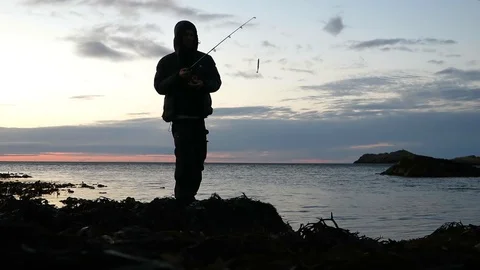 Silhouette fisherman with down jacket throwing rod Stock Footage 87729539