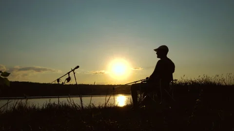 Silhouette of fisherman drinking alcohol at sunset Stock Footage 135034853