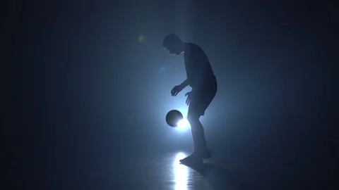 Silhouette of football player stuffing ball against blue spotlight. Slow motion Stock Footage 112830785