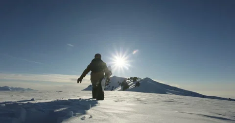 Silhouette of freeride snowboarder walking through deep snow in the mountains Stock Footage 255886934