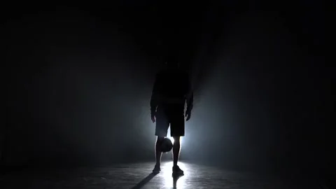 Silhouette of freestyler stuffing the ball at studio in dark. Slow motion Stock Footage 112830475