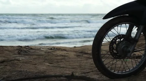 Silhouette of front wheel of motorcycle that is parked on the beach Stock Footage 63443183