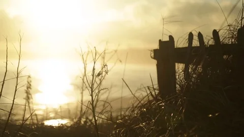 Silhouette of gate next to beach as the sun sets reflecting on the sea. 動画素材 72672166