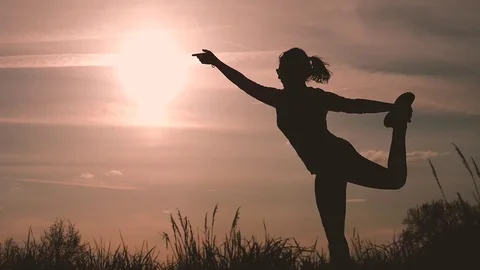 Silhouette of a girl performs some dance poses in backlight during sunset in the Stock Footage 74107600