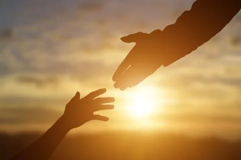 Silhouette of giving a helping hand, hope and support each other over sunset Stock Photos