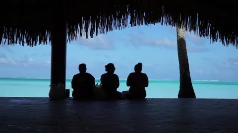 A silhouette of a group of friends sitting down looking out towards the ocean in 스톡 동영상 68531100