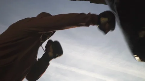 Silhouette of guy, boxer exercising, punching bag, close up, low angle, blue sky Stock Footage 98493852