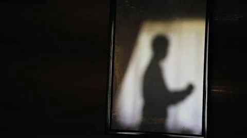 The silhouette of the guy dressing in the room is reflected from the mirror Stock Footage 147119961