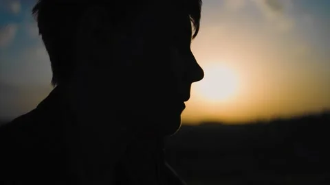 The silhouette of a guy sitting on the background of a beautiful sunset sky Stock Footage 154369379