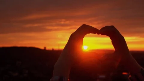 Silhouette hand in heart shape with sunset inside. Stock Footage 76733995