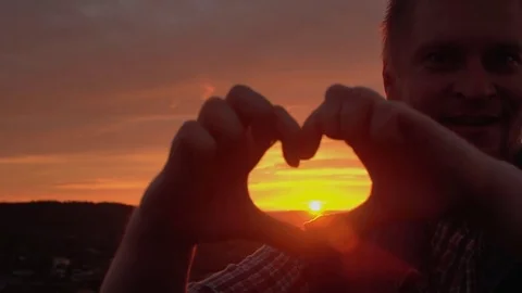 Silhouette hand in heart shape with sunset inside. Stock Footage 76734130