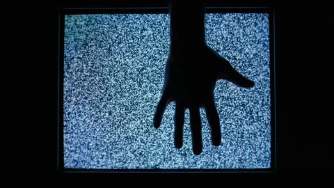 Silhouette Hand Reaching Towards Static Television Screen in Dark Room Stock Footage 335634157