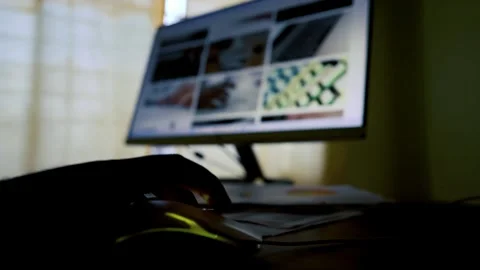 Silhouette of a hand using a computer mouse with a blurred monitor in the b.. 動画素材 315981105