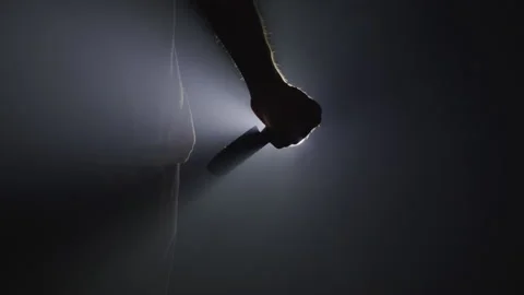 Silhouette of a Hand Wielding a Dagger in Front of a Shining Light Stock Footage 208758229