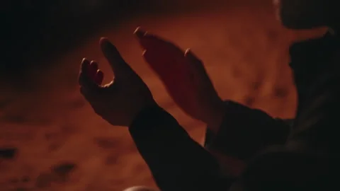 Silhouette of hands clapping by warm campfire light at night Stock Footage 337644315