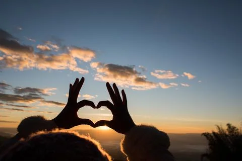 Silhouette hands forming a heart shape with sunrise Stock Photos