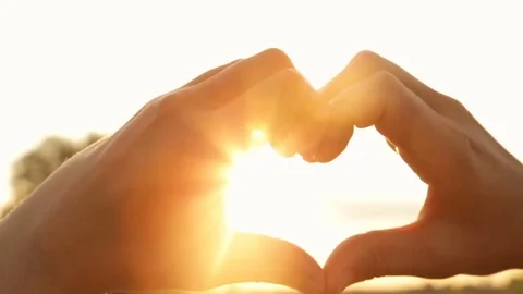 Silhouette of hands in the shape of heart with rays of the setting sun Vídeo Stock 77598801
