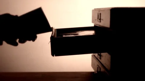 Silhouette of hands taking paperwork from a small set of drawers. Stock Footage 70386127