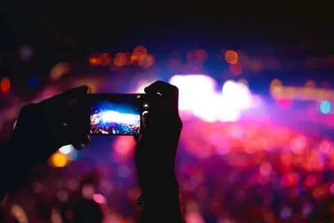 Silhouette of hands using camera phone to take pictures at music festival Stock Photos