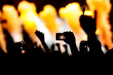Silhouette of hands using camera phone to take pictures and videos at live co Stock Photos