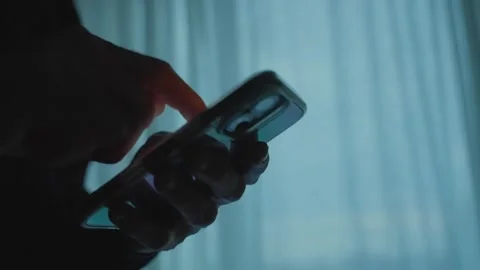 Silhouette of hands using a smartphone while scrolling Видео 339303148