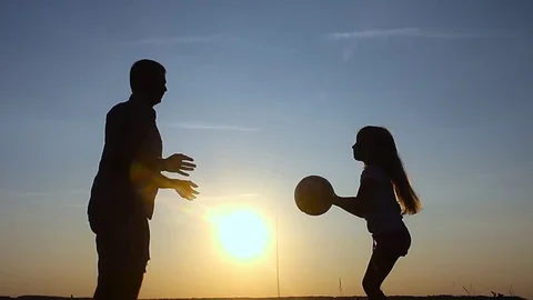 Silhouette of happy father and daughter who playing with the ball on the meadow Stock Footage
