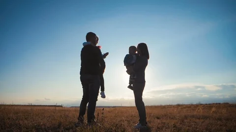 A silhouette happy young family. Happy family at sunset. Father, mother and two Stock Footage