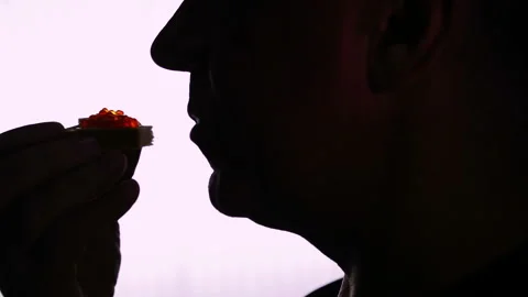 Silhouette of the head of a man who eats a sandwich with red caviar Stock Footage 101496002