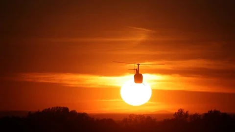 Silhouette of a helicopter on a background of bright sun at sunset. Blockbuster  Stock Footage 100284656