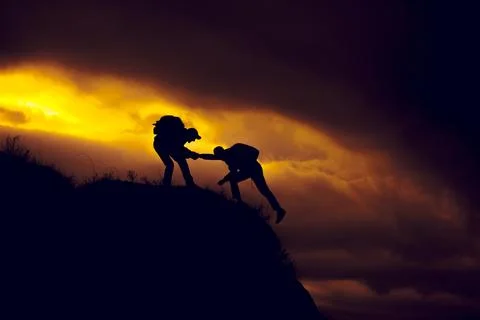 Silhouette of helping hand between two climber Stock Photos